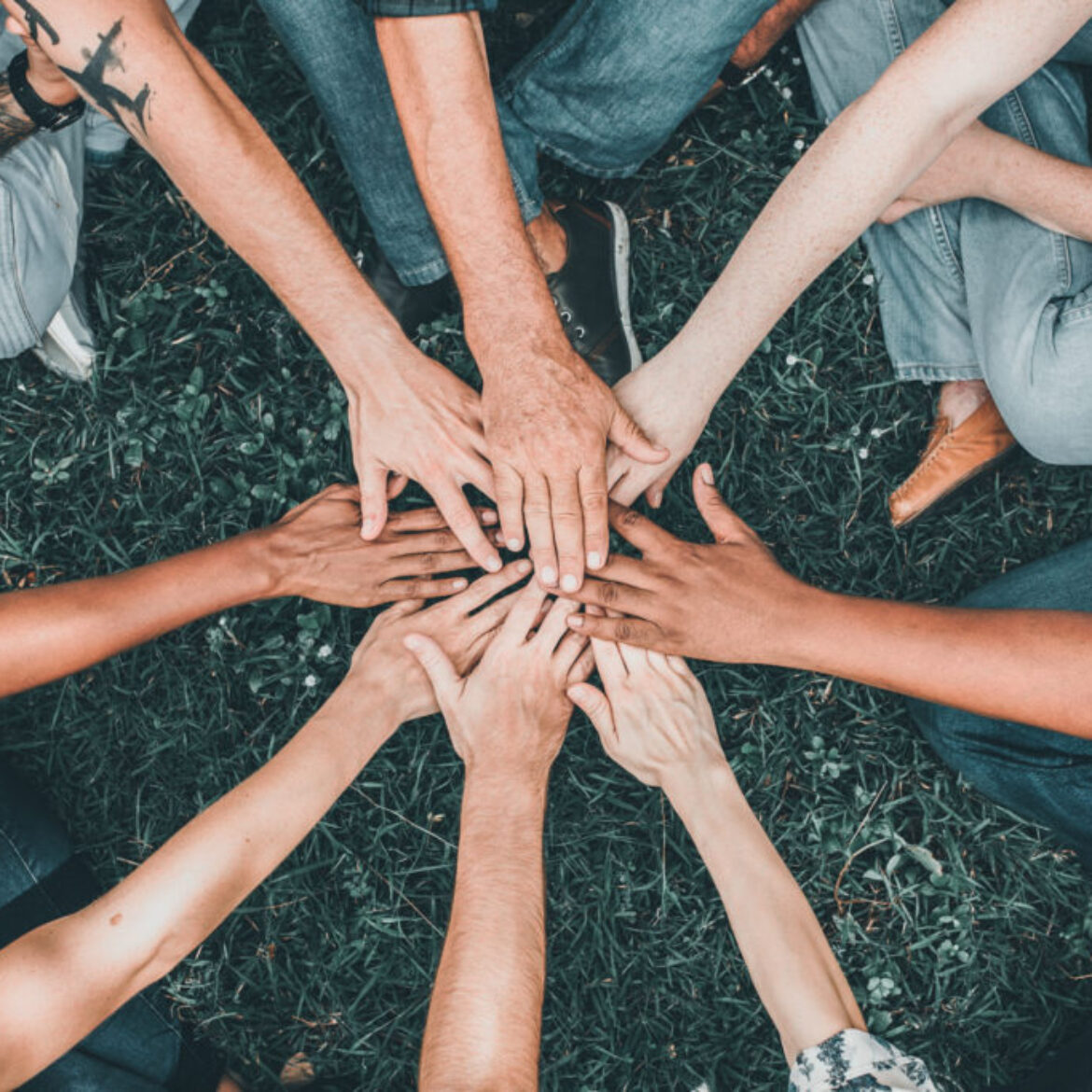 People stacking hands together in the park