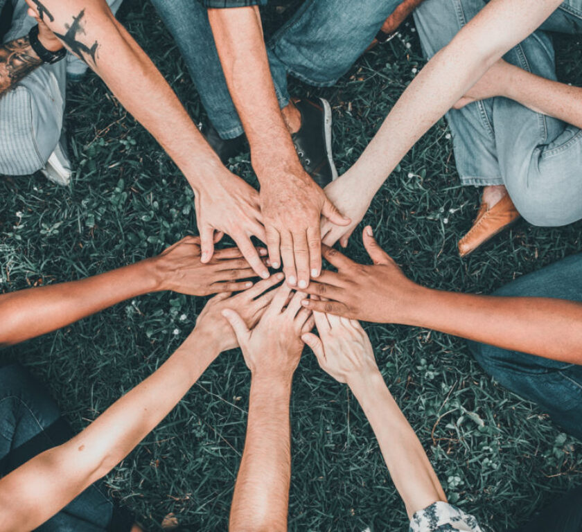 People stacking hands together in the park