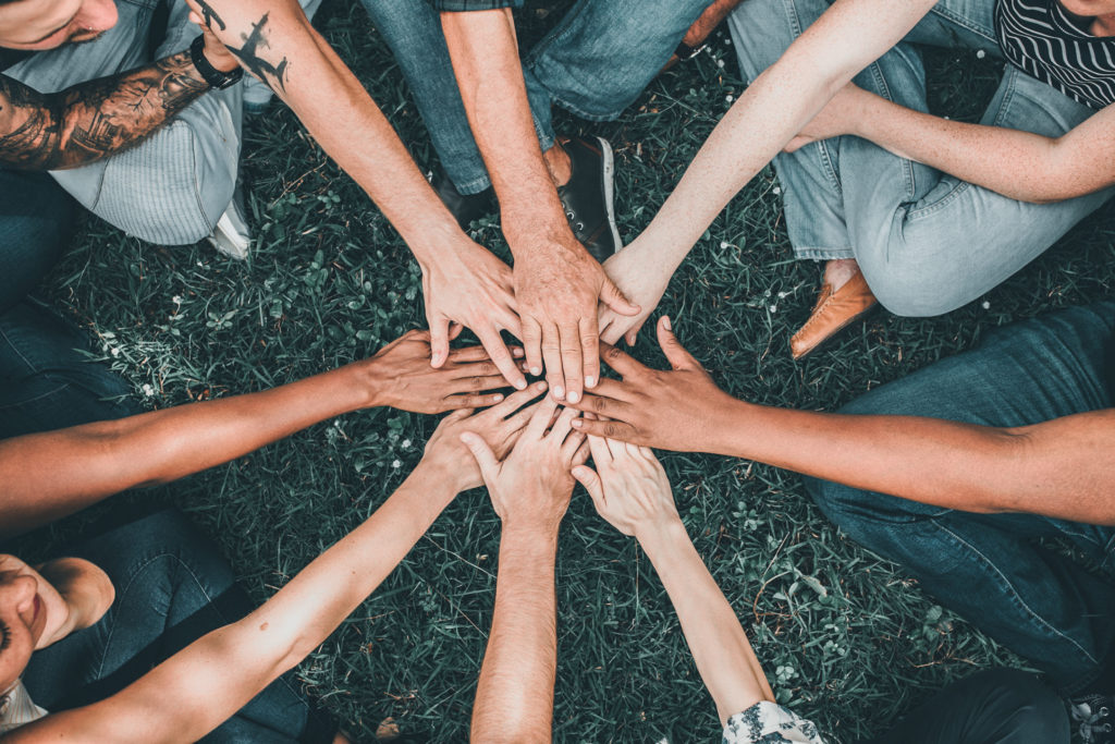 People stacking hands together in the park