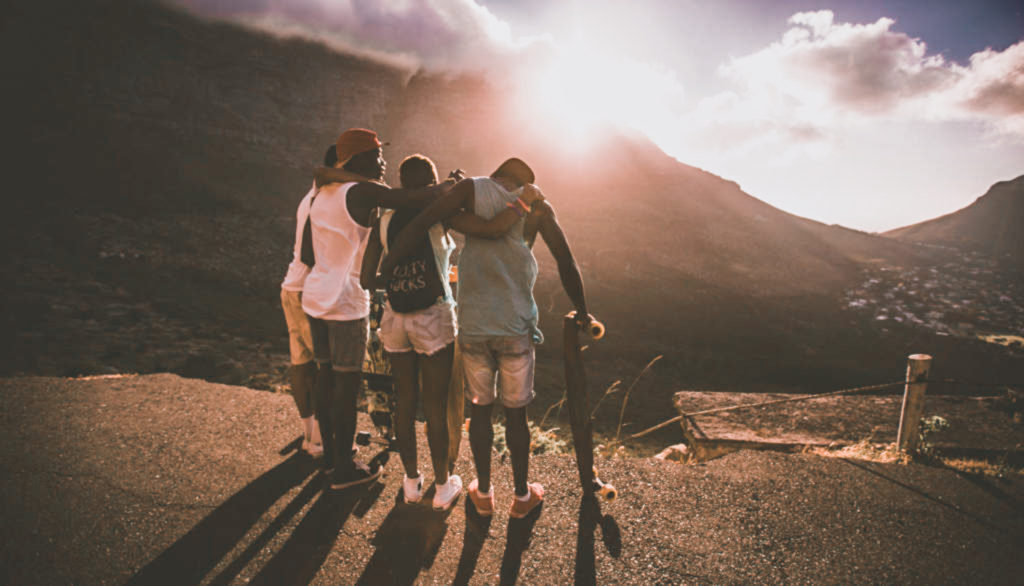 Group of happy teen friends standing together with longboards