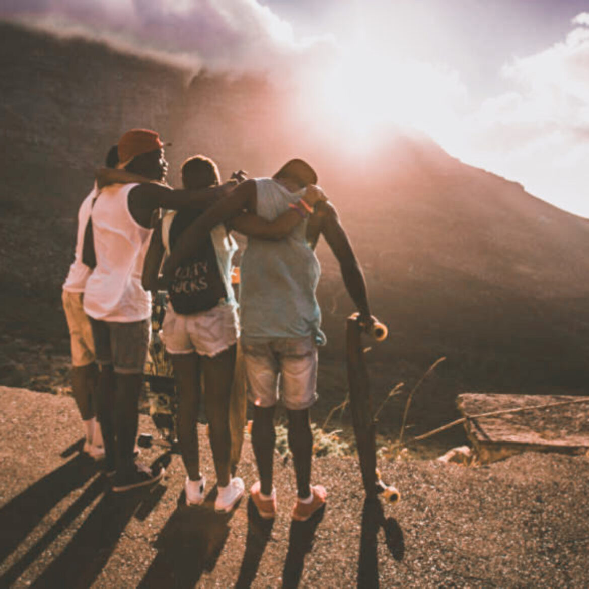 Group of happy teen friends standing together with longboards